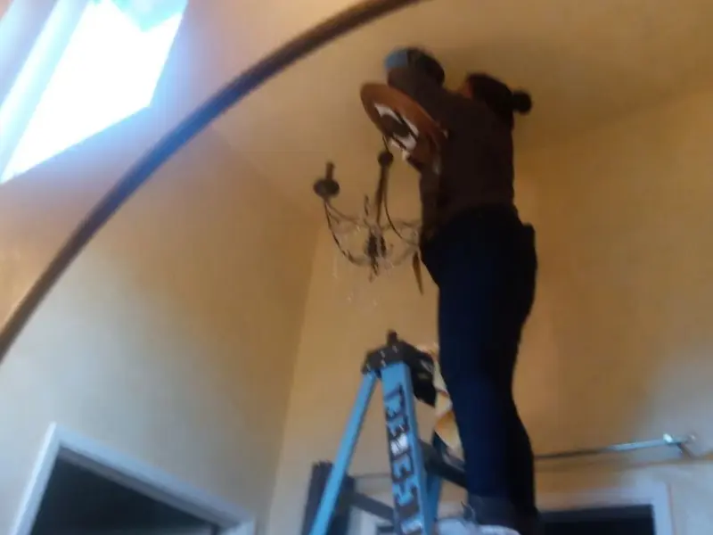 Electrician installing a chandelier in a Snyderville residence